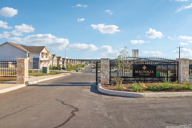 view of street with curbs, a gate, street lighting, a gated entry, and sidewalks