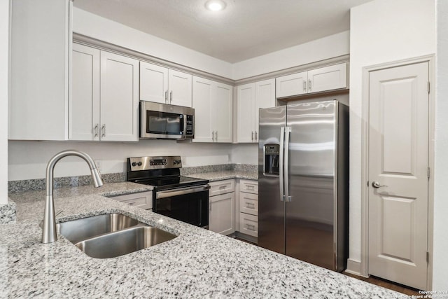 kitchen featuring light stone countertops, a sink, recessed lighting, and appliances with stainless steel finishes