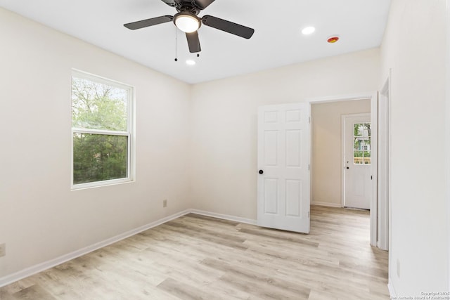 empty room featuring baseboards, a wealth of natural light, and light wood-style floors