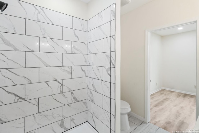 full bathroom with baseboards, toilet, and tiled shower