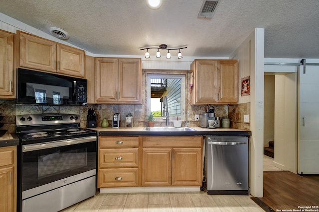 1340 Hinch, New Braunfels, TX 78132 - kitchen with a sink, a textured ceiling, a barn door, tasteful backsplash, and appliances with stainless steel finishes