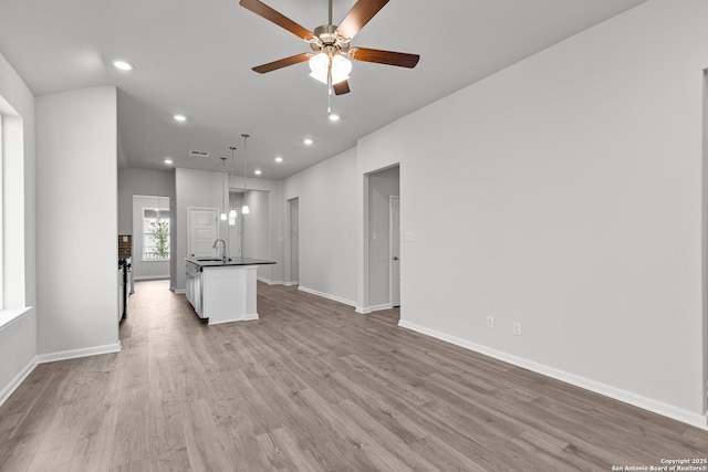 unfurnished living room featuring a sink, a ceiling fan, recessed lighting, and light wood-style flooring