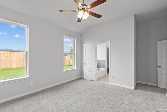 unfurnished bedroom featuring carpet flooring, ceiling fan, baseboards, ensuite bathroom, and vaulted ceiling