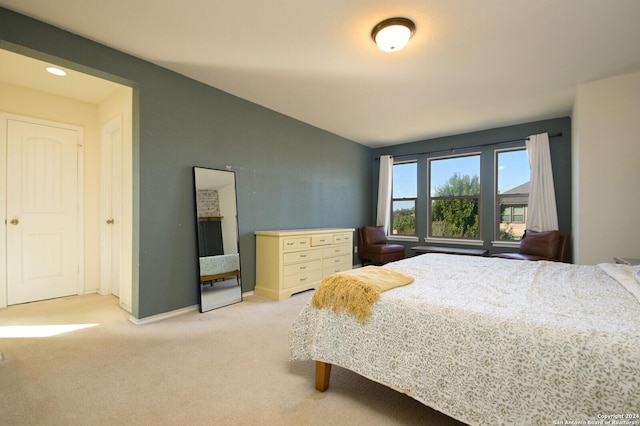 bedroom featuring light carpet, vaulted ceiling, and baseboards