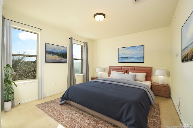 bedroom featuring baseboards, visible vents, and light colored carpet