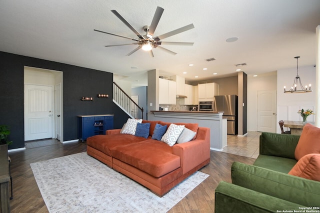 living room featuring recessed lighting, wood finished floors, visible vents, stairs, and ceiling fan with notable chandelier
