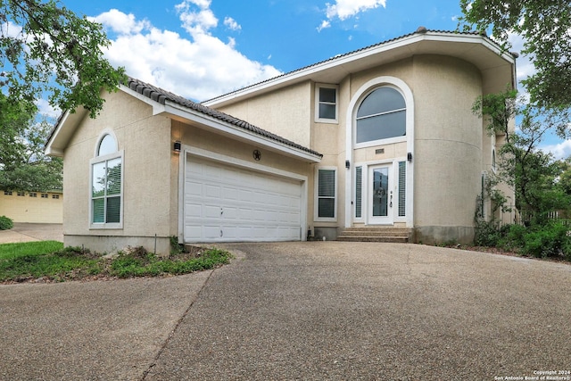 traditional-style house featuring an attached garage, aphalt driveway, and stucco siding