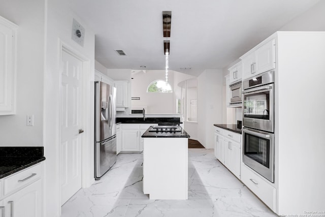 kitchen featuring a peninsula, dark countertops, stainless steel appliances, and white cabinetry