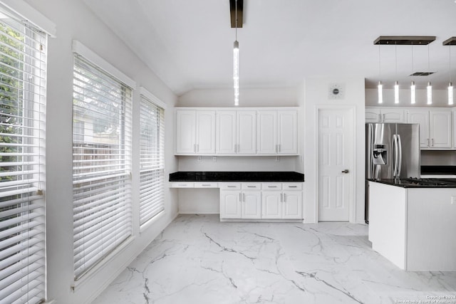 kitchen featuring dark countertops, marble finish floor, stainless steel fridge, and white cabinetry