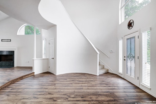 entryway featuring wood finished floors, high vaulted ceiling, stairway, and a healthy amount of sunlight