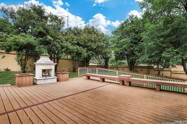 deck featuring a fenced backyard and an outdoor fireplace