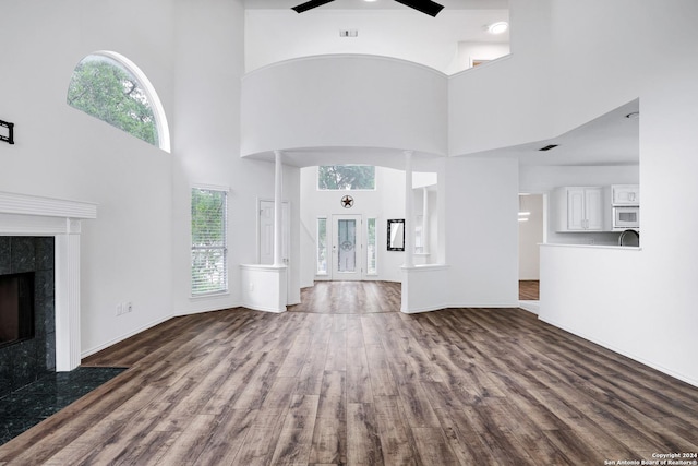 unfurnished living room with a high ceiling, dark wood-style flooring, and a fireplace