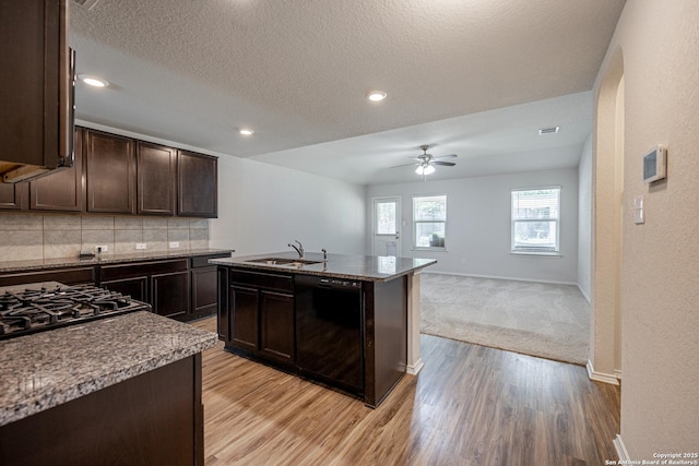 kitchen featuring a ceiling fan, decorative backsplash, dark brown cabinetry, a sink, and light wood finished floors