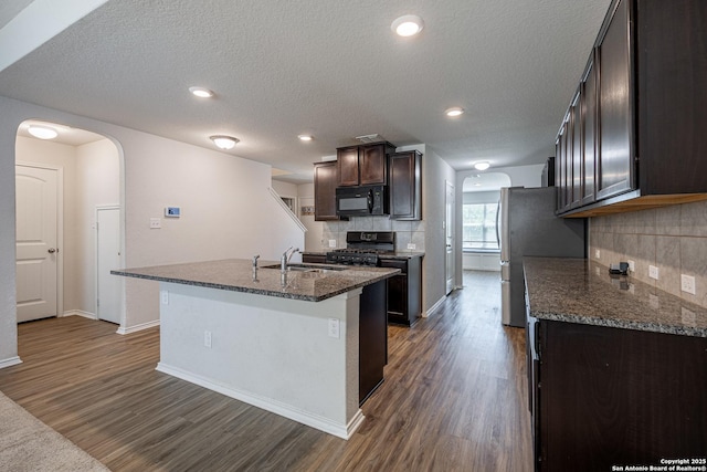 kitchen with arched walkways, black appliances, and dark wood-type flooring