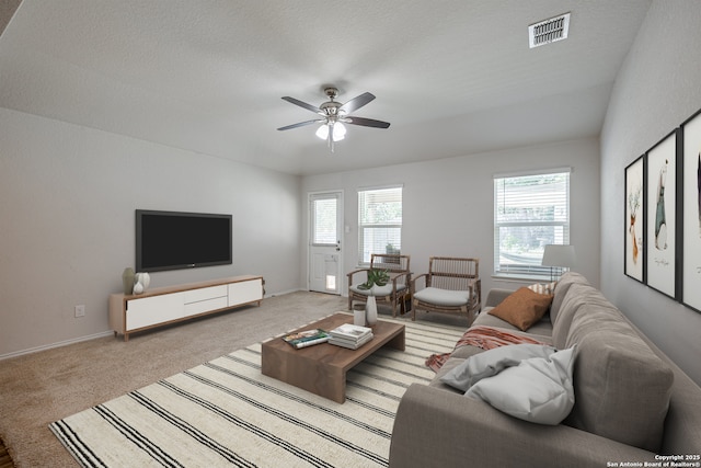 living area with visible vents, a ceiling fan, baseboards, and light carpet