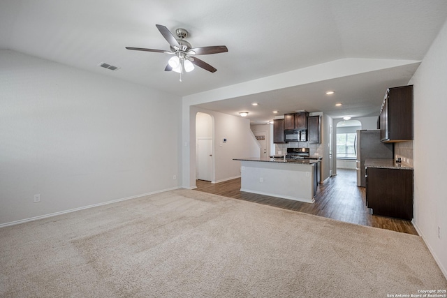 kitchen featuring dark brown cabinets, black microwave, arched walkways, dark carpet, and visible vents