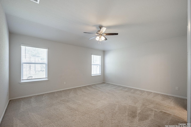unfurnished room featuring light colored carpet, a ceiling fan, and baseboards