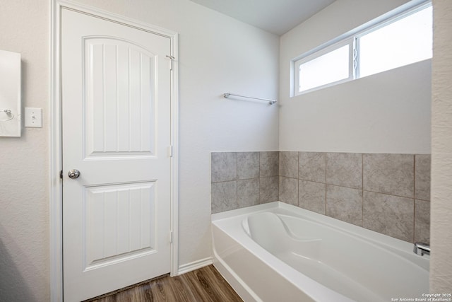 bathroom with a garden tub and wood finished floors