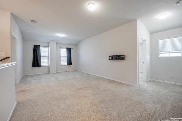 unfurnished room featuring vaulted ceiling, light carpet, and visible vents