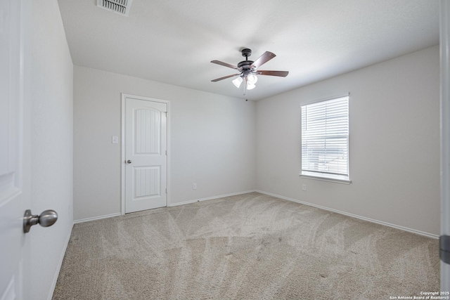carpeted empty room with visible vents, a ceiling fan, and baseboards