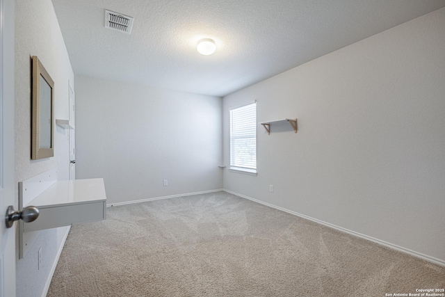 unfurnished bedroom featuring light colored carpet, baseboards, visible vents, and a textured ceiling