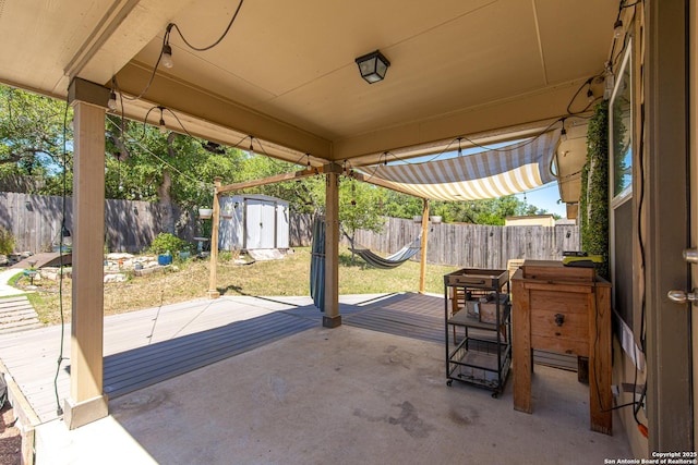 view of patio / terrace with a storage unit, a fenced backyard, outdoor dining space, and an outdoor structure