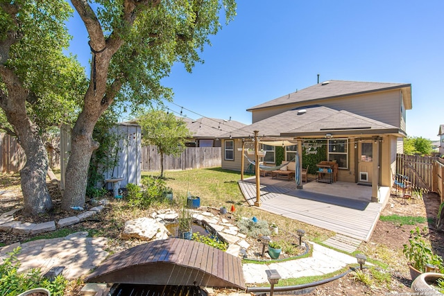 back of property featuring a fenced backyard, a wooden deck, a shingled roof, and a lawn