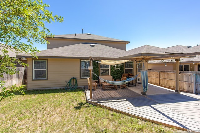 back of property featuring a lawn, a shingled roof, fence, and a wooden deck