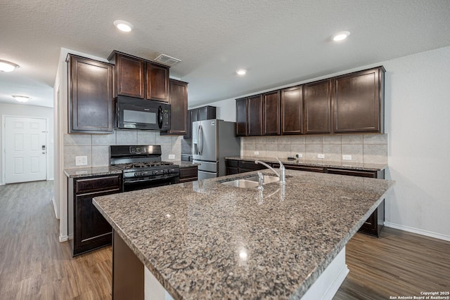 kitchen featuring dark brown cabinetry, a sink, baseboards, visible vents, and black appliances