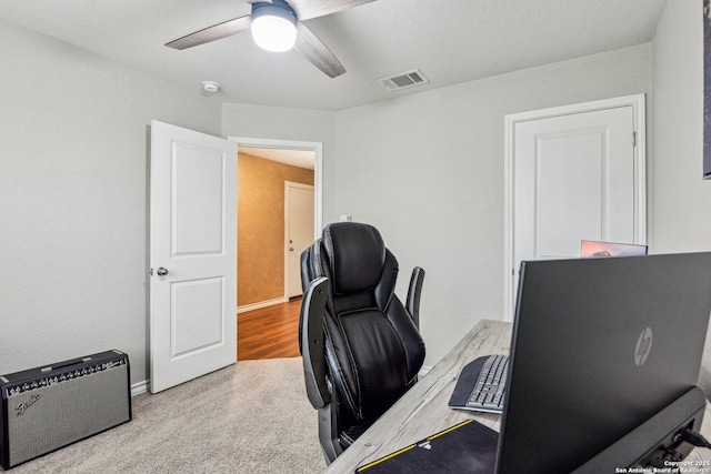 office space with baseboards, a ceiling fan, visible vents, and carpet