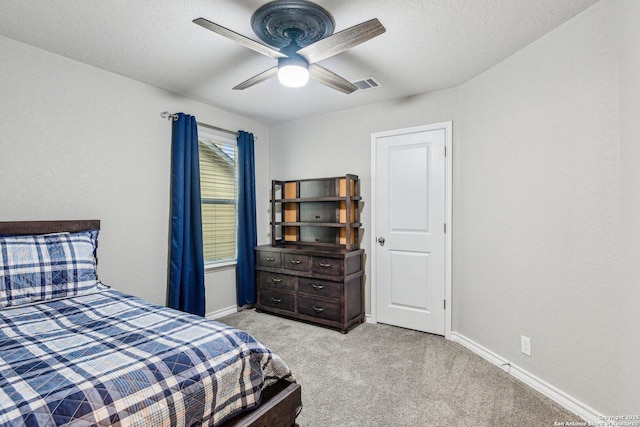 bedroom featuring visible vents, baseboards, a textured ceiling, light colored carpet, and ceiling fan