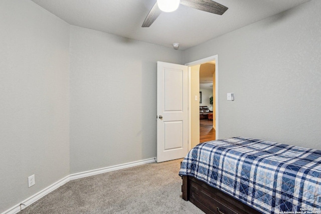 bedroom with light colored carpet, baseboards, and a ceiling fan
