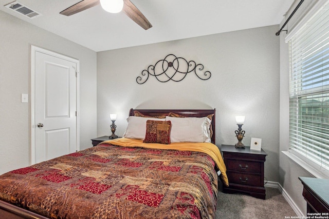 carpeted bedroom with baseboards, a ceiling fan, multiple windows, and visible vents