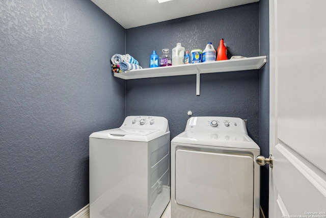 clothes washing area featuring a textured wall, washer and clothes dryer, and laundry area