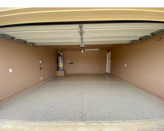 garage featuring baseboards and water heater