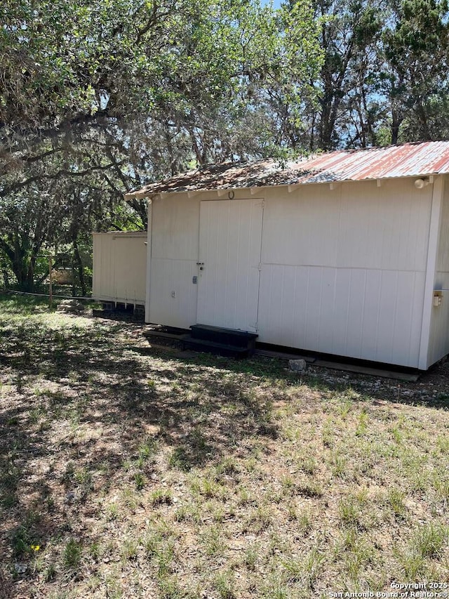 view of home's exterior featuring a storage shed, metal roof, and an outbuilding