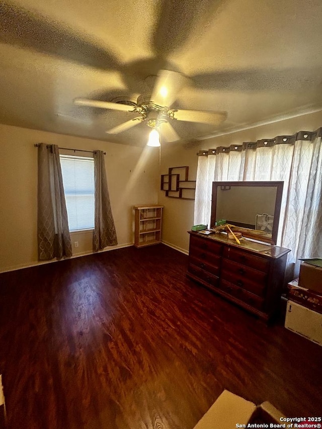 unfurnished bedroom featuring ceiling fan, baseboards, wood finished floors, and a textured ceiling