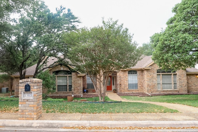 view of front of home with brick siding, a shingled roof, and a front lawn