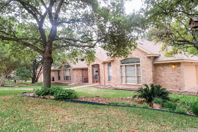 back of house featuring brick siding, a lawn, and a garage