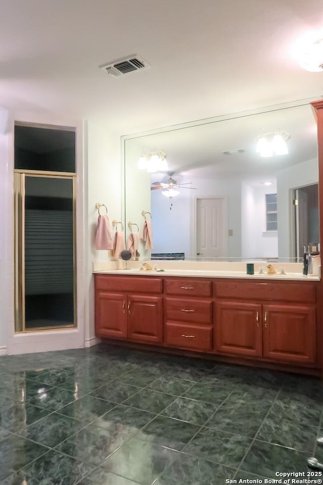 bathroom featuring a sink, double vanity, a stall shower, visible vents, and a ceiling fan
