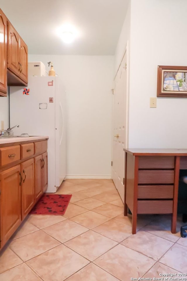 kitchen featuring light countertops, freestanding refrigerator, and light tile patterned flooring