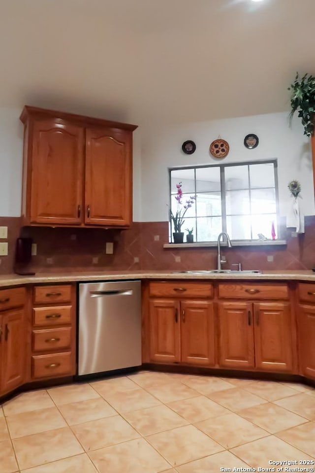 kitchen featuring brown cabinetry, backsplash, stainless steel dishwasher, and a sink
