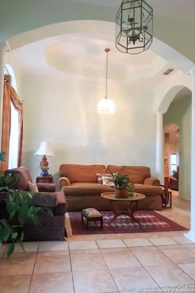 living area featuring light tile patterned flooring, a chandelier, arched walkways, visible vents, and decorative columns