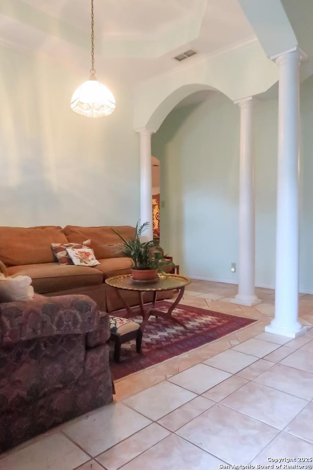 living room featuring light tile patterned floors, arched walkways, ornamental molding, visible vents, and ornate columns