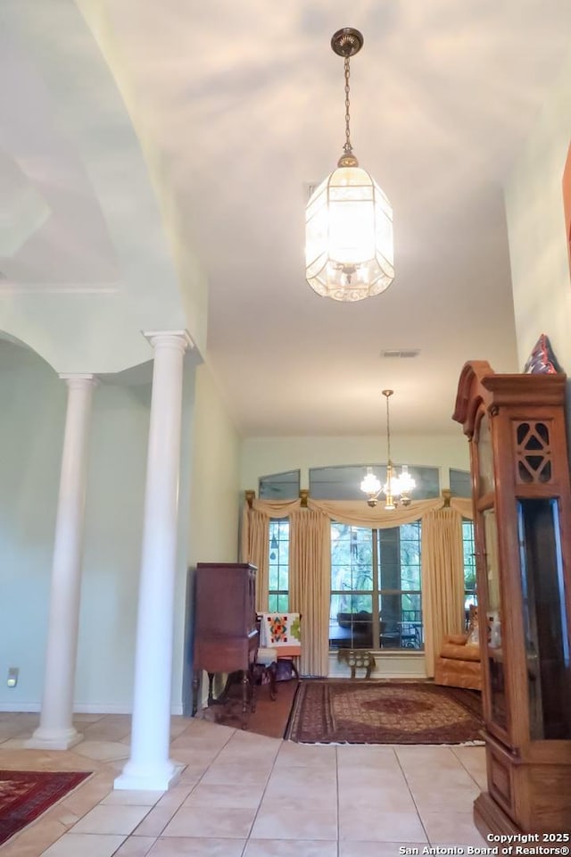 entrance foyer with light tile patterned floors, an inviting chandelier, visible vents, and ornate columns