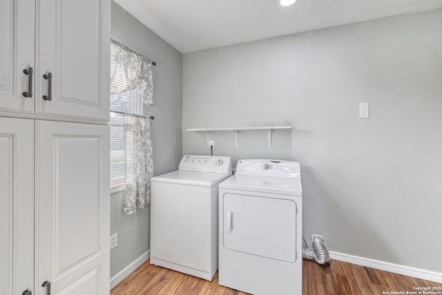 laundry room featuring washing machine and clothes dryer, light wood-style flooring, baseboards, and cabinet space