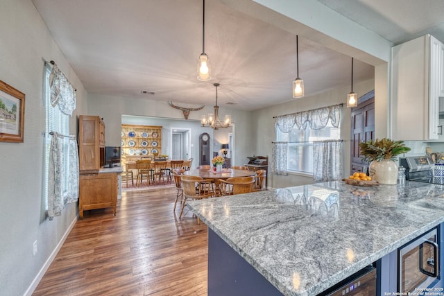 kitchen featuring a peninsula, baseboards, wood finished floors, pendant lighting, and light stone countertops