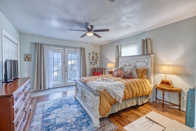 bedroom with wood finished floors, access to outside, french doors, and a textured ceiling