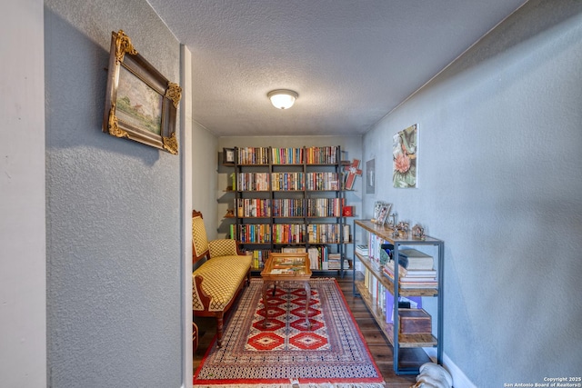 sitting room featuring a textured wall, wood finished floors, and a textured ceiling
