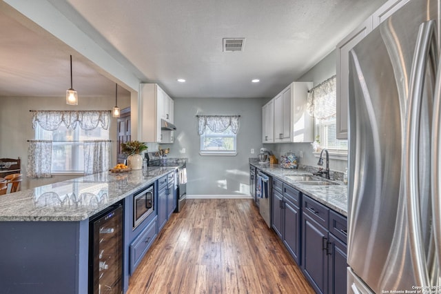 kitchen featuring a sink, visible vents, blue cabinetry, appliances with stainless steel finishes, and wine cooler